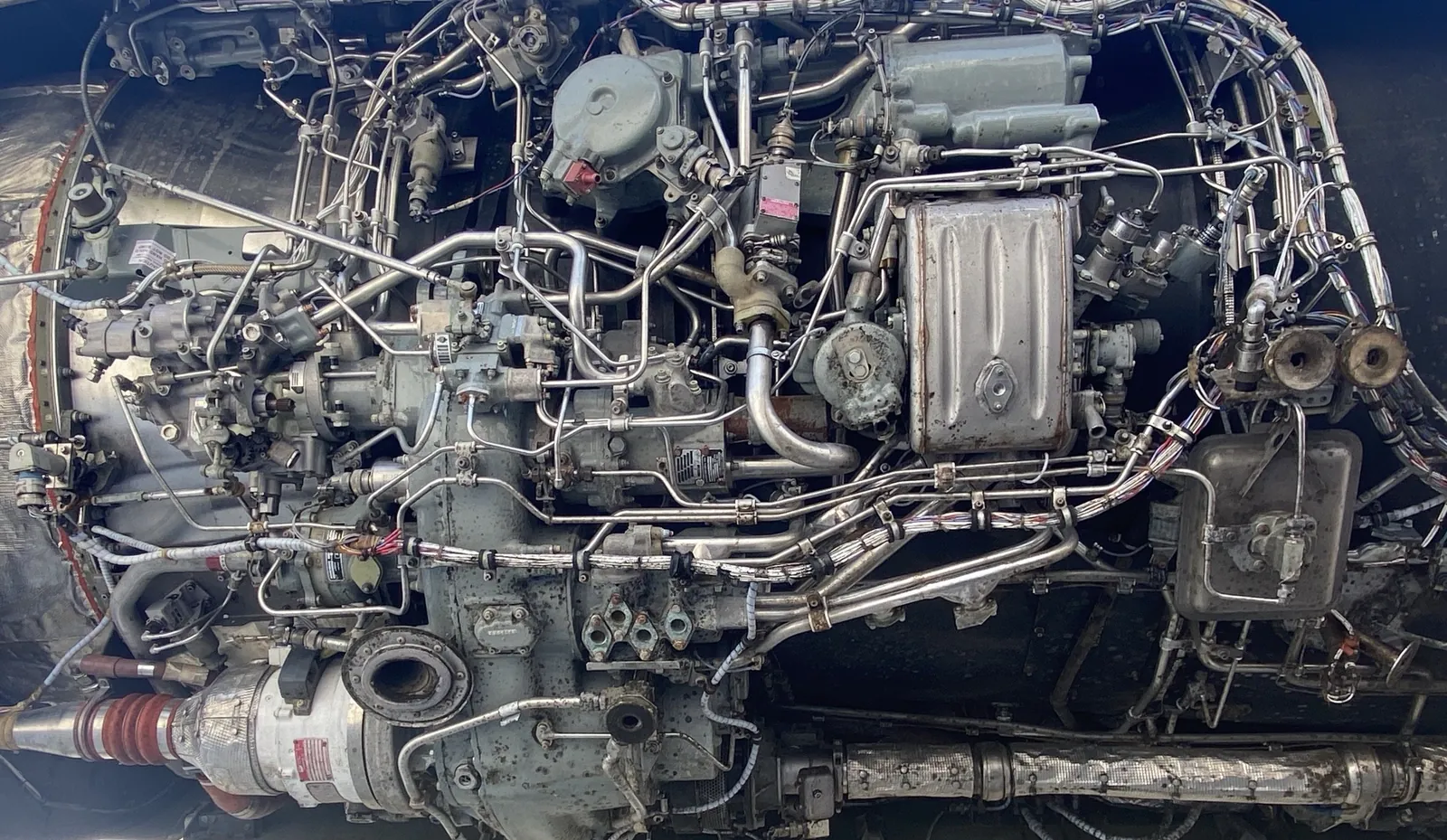 Jet engine with the cowling open, showing accessories, fuel lines and wiring